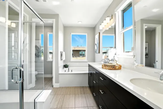 a bathroom with a double vanity sink a large mirror and a bathtub