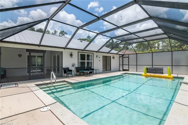 a view of a backyard with lawn chairs under an umbrella