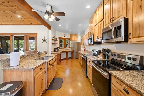 a kitchen with stainless steel appliances granite countertop a sink a stove and a wooden cabinets
