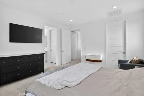 a spacious bedroom with a bed and a flat screen tv