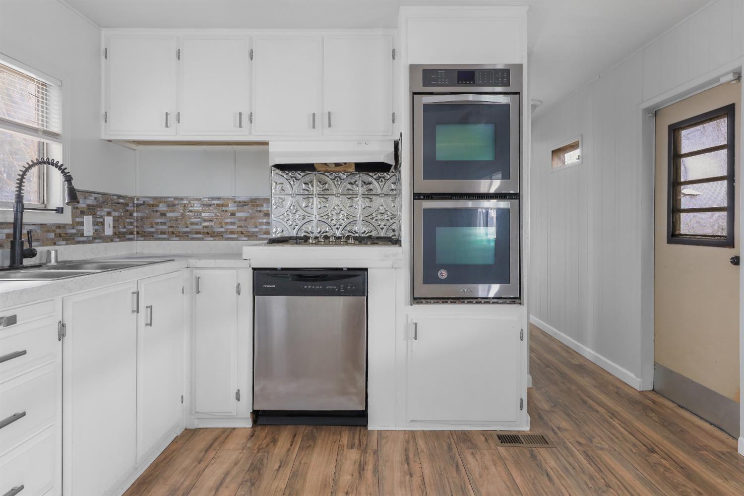 a kitchen with granite countertop white cabinets and a wooden floor