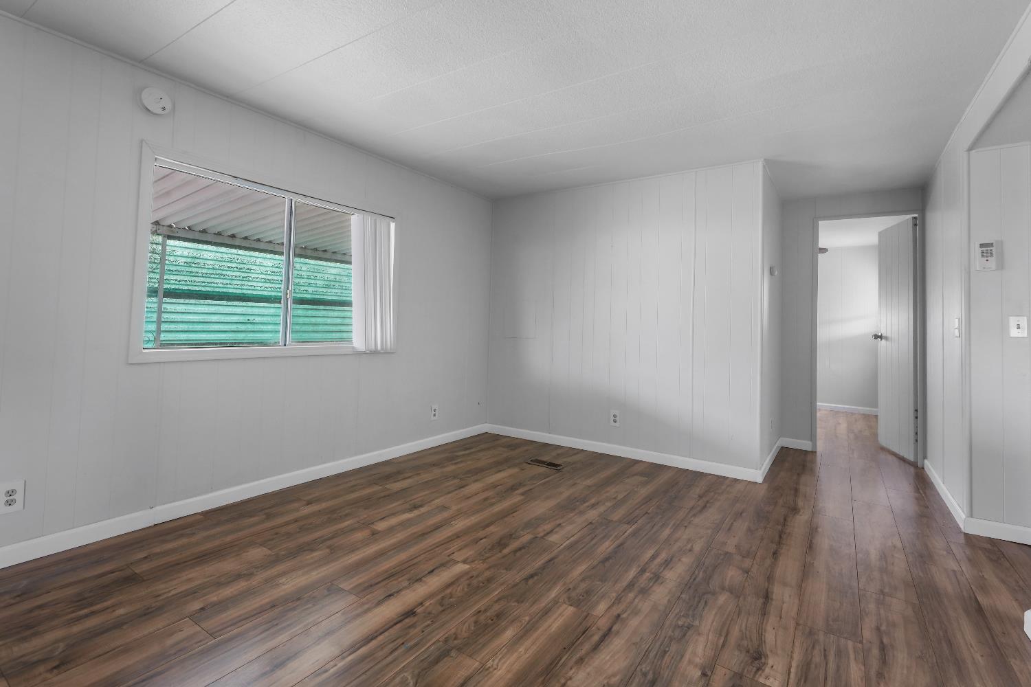 19142 North Jack Tone Road, Unit 34 Lockeford, CA 95237 - Photo 12 of 21 a view of an empty room with wooden floor and a window