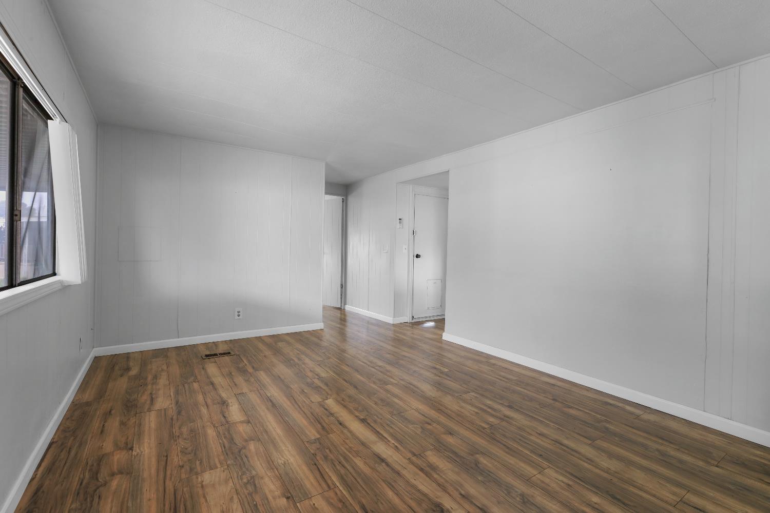 19142 North Jack Tone Road, Unit 34 Lockeford, CA 95237 - Photo 13 of 21 a view of an empty room with wooden floor and a window