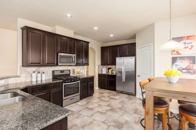 a kitchen with stainless steel appliances granite countertop a stove a sink a microwave a refrigerator and cabinets