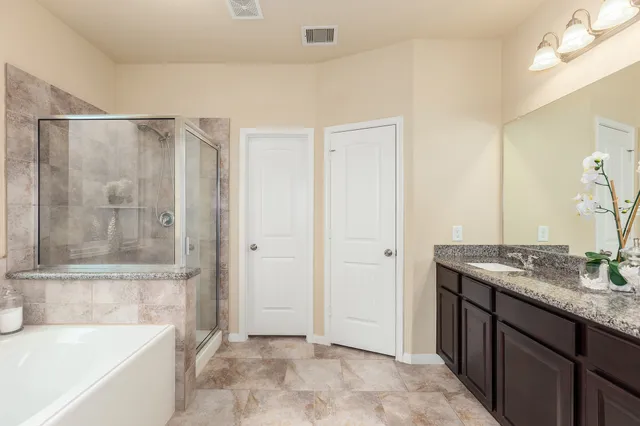 a bathroom with a granite countertop sink a mirror and a bathtub