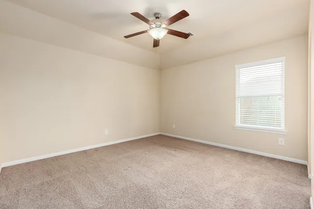 an empty room with a window and a fan