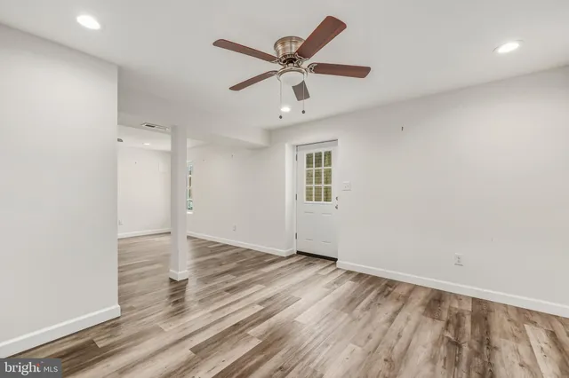 an empty room with wooden floor and ceiling fan