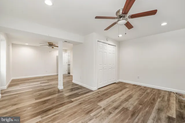 an empty room with wooden floor ceiling fan and window