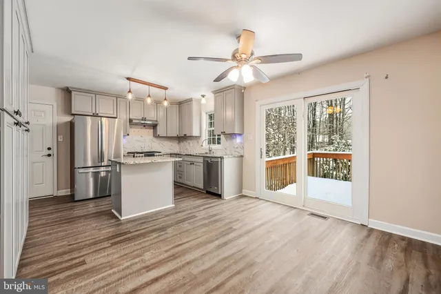 a kitchen with stainless steel appliances a stove top oven a refrigerator cabinets and wooden floor