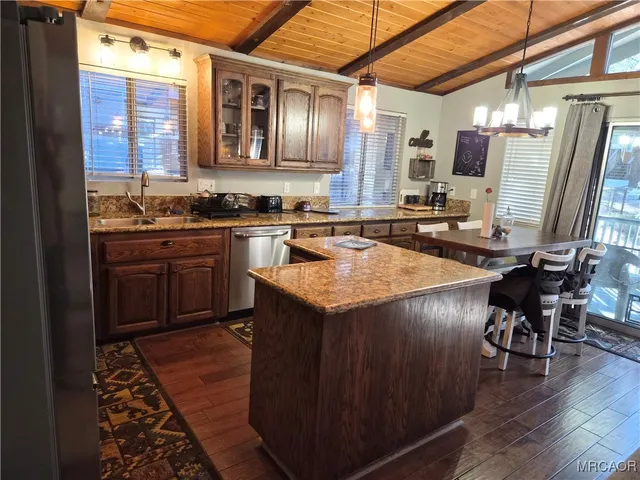 a kitchen with stainless steel appliances granite countertop wooden cabinets a sink dishwasher a stove and a refrigerator