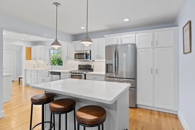 a kitchen with granite countertop a table chairs stove and refrigerator