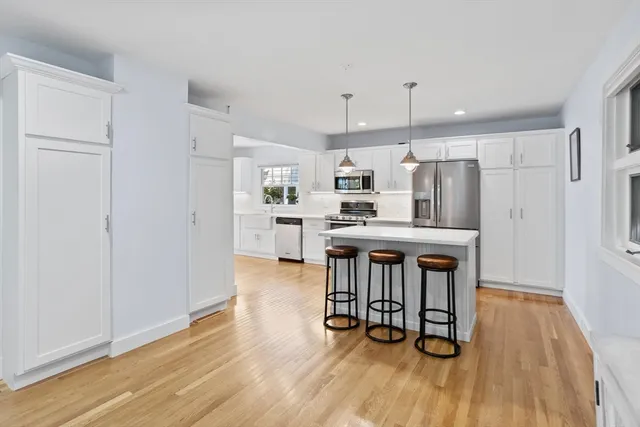 a kitchen with stainless steel appliances a dining table chairs refrigerator and cabinets