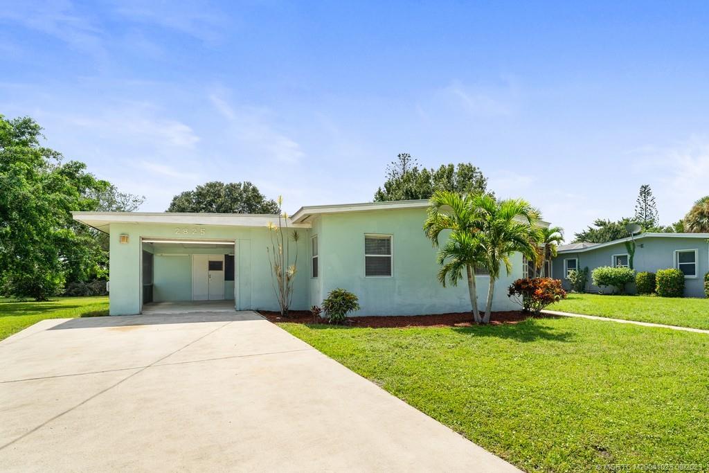 2825 Southeast Pocatella Road Port St. Lucie, FL 34952 - Photo 24 of 36 a front view of a house with a yard and palm trees