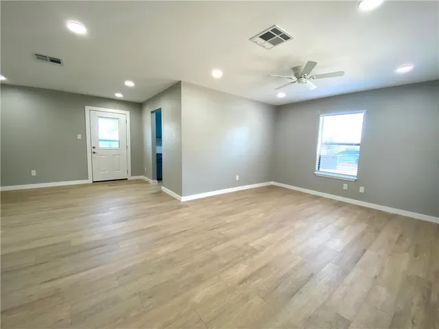 an empty room with wooden floor and windows