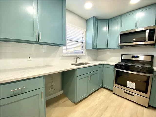 a kitchen with stainless steel appliances granite countertop a sink and a microwave