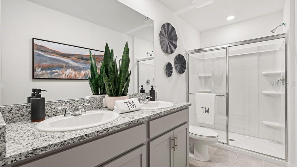 690 Gladstone Way Mount Dora, FL 32757 - Photo 11 of 25 a bathroom with a granite countertop sink a toilet and a mirror