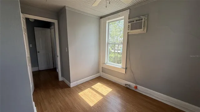 a view of an empty room with wooden floor and stairs