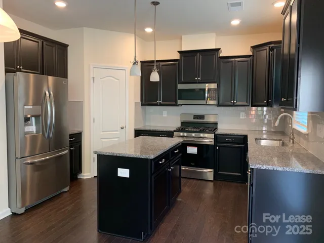 a kitchen with stainless steel appliances granite countertop a refrigerator a stove a sink and a microwave