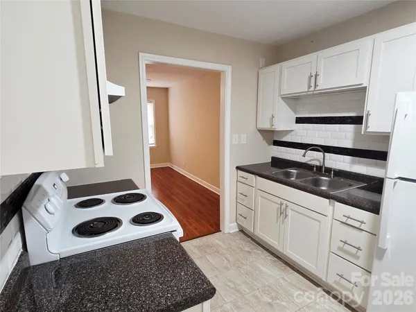 a kitchen with granite countertop a sink a stove and cabinets