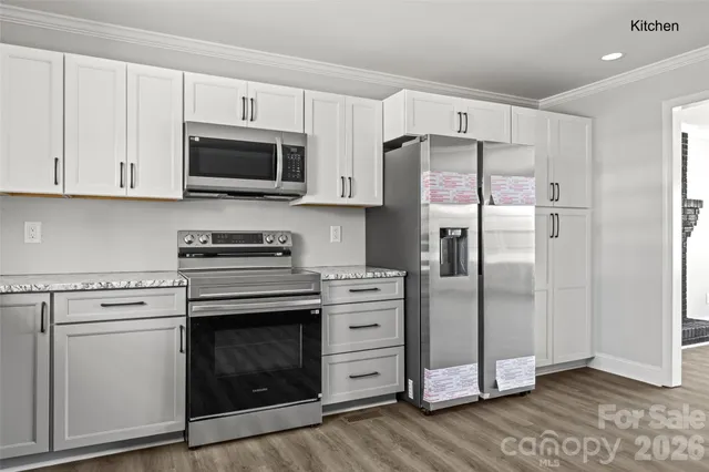 a kitchen with stainless steel appliances white cabinets white stove a refrigerator and a microwave