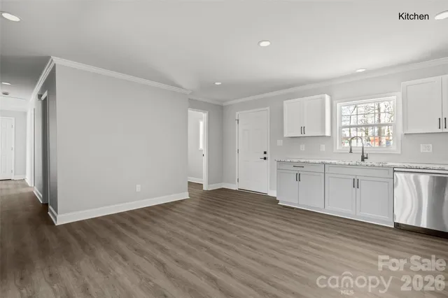 a view of a kitchen with white cabinets and wooden floor