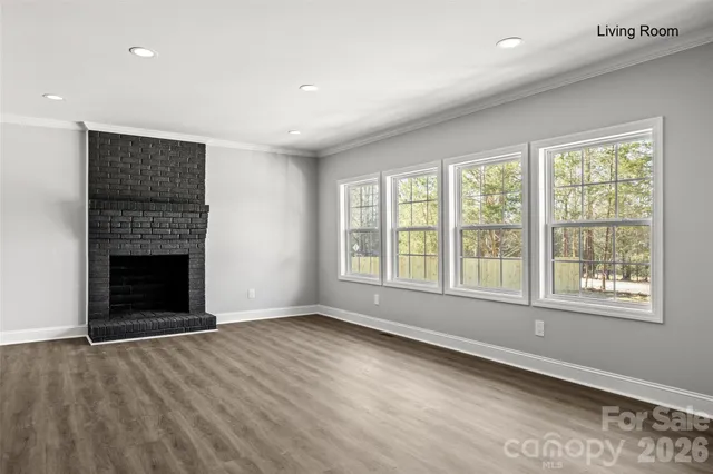 an empty room with windows and fireplace