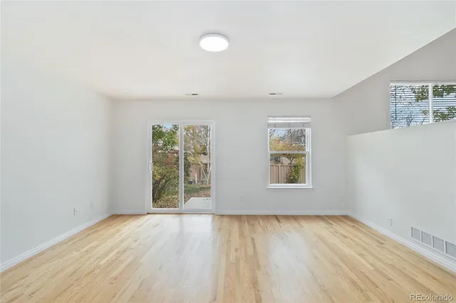 an empty room with wooden floor and windows