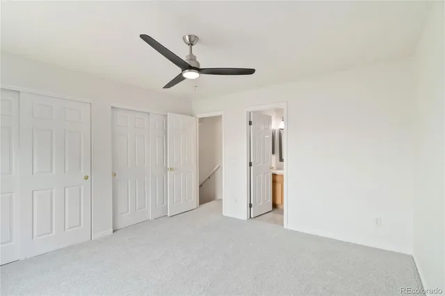 a view of a livingroom with a ceiling fan & windows