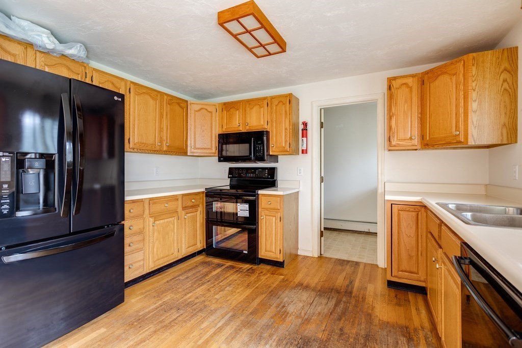58 Peabody Road, Unit L Shirley, MA 01464 - Photo 15 of 22 a kitchen with granite countertop a stove top oven a sink dishwasher and a refrigerator with wooden floor