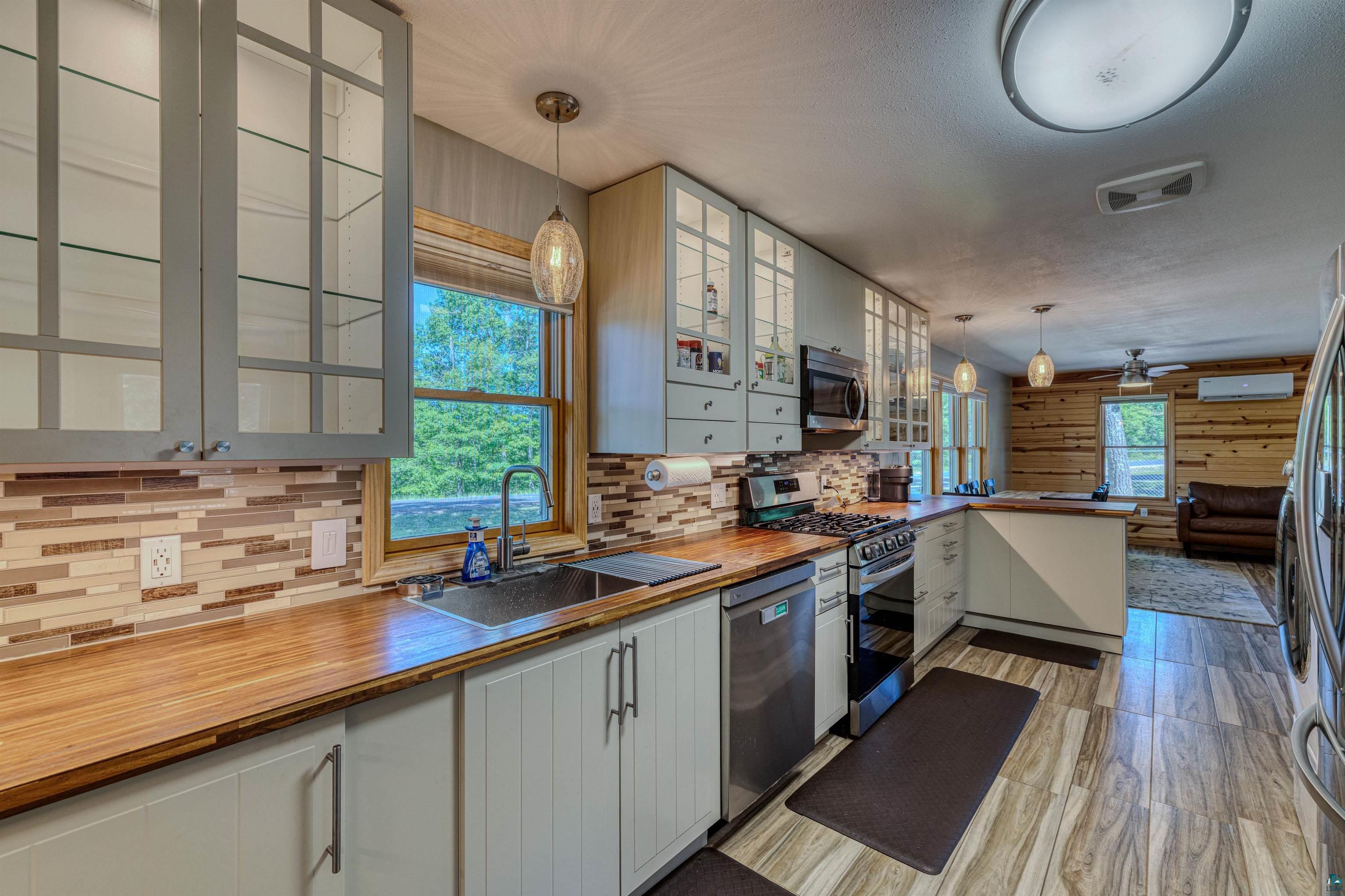 66075 Rooster Road Iron River, WI 54847 - Photo 27 of 52 Modern kitchen featuring wood-finish flooring, light cabinetry, stainless steel appliances, and wood countertops