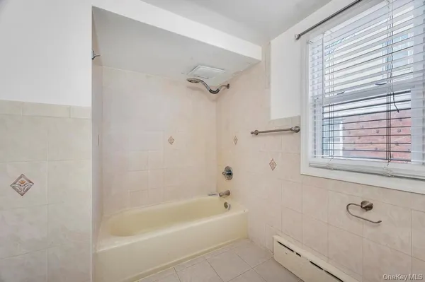 a bathroom with a bathtub a window and a shower
