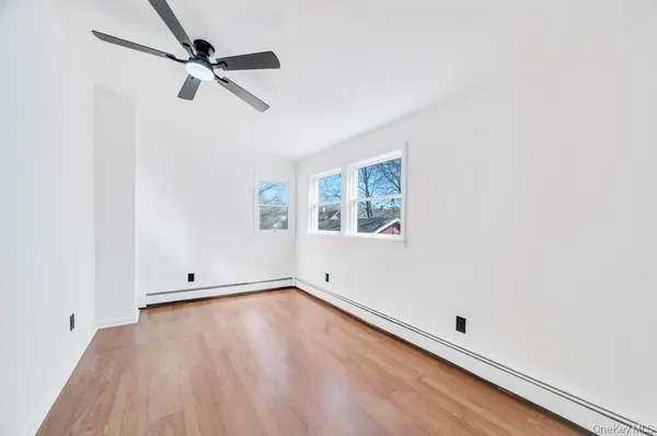 an empty room with wooden floor fan and windows