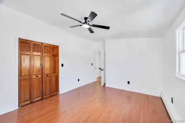 an empty room with wooden floor closet and windows