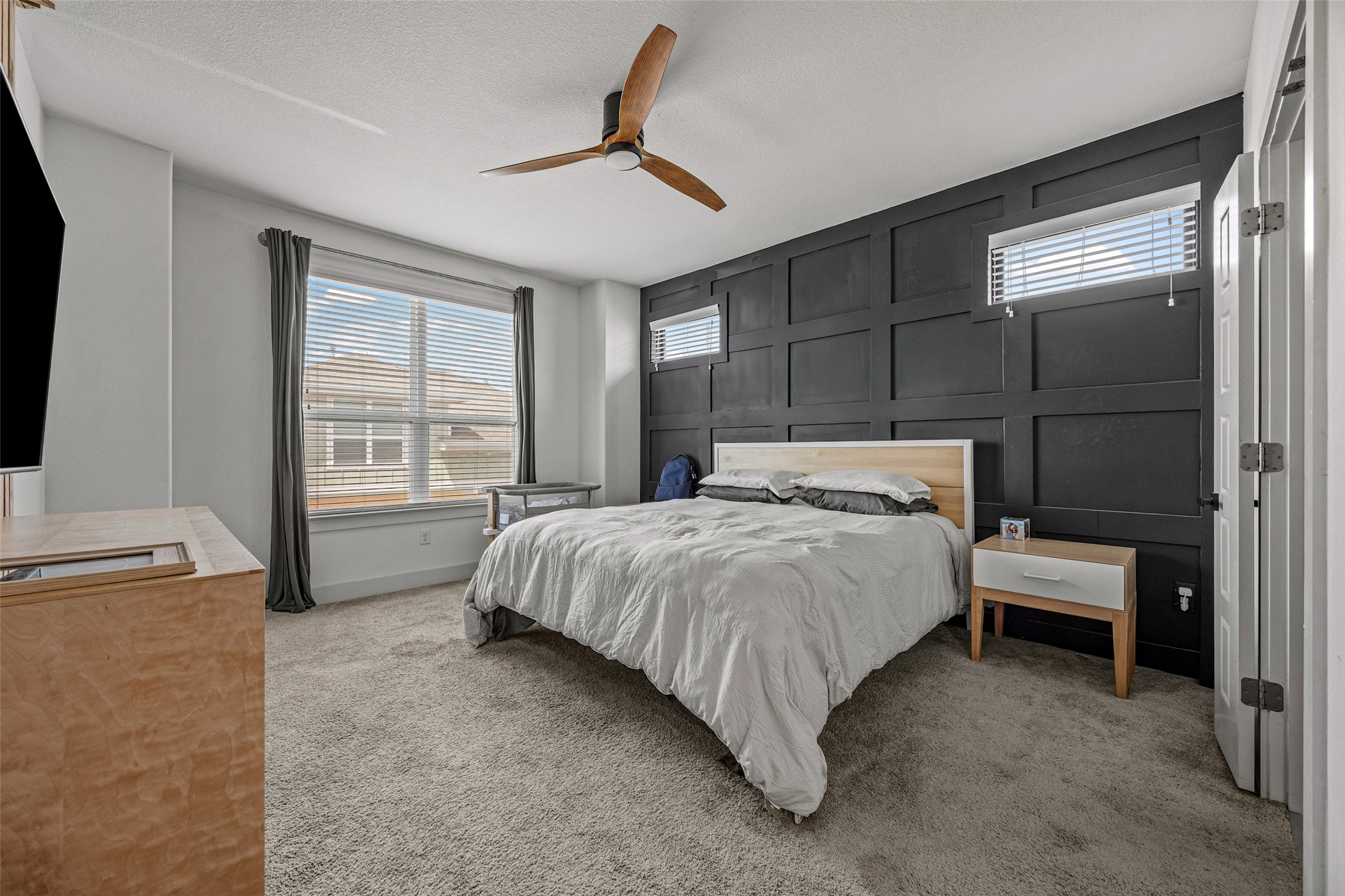 1408 Homespun Road Austin, TX 78745 - Photo 13 of 20 A restful primary bedroom showcases soft carpeting and a striking accent wall, offering a serene escape.