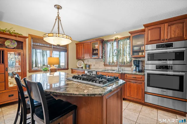 a kitchen with stainless steel appliances granite countertop a stove a sink dishwasher a dining table and chairs with wooden floor