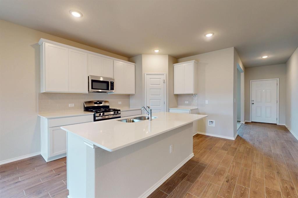 4509 Beacon Bay Drive Austin, TX 78747 - Photo 2 of 30 Kitchen featuring white cabinets, stainless steel appliances, wood tiled floors, an island with sink, and recessed lighting