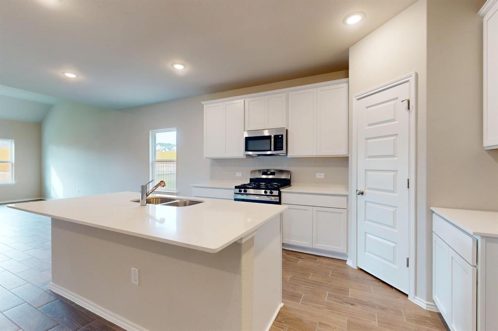 4509 Beacon Bay Drive Austin, TX 78747 - Photo 3 of 30 Kitchen with stainless steel appliances, wood finish floors, white cabinets, a center island with sink, and recessed lighting