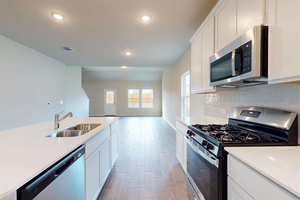 4509 Beacon Bay Drive Austin, TX 78747 - Photo 4 of 30 Kitchen featuring stainless steel appliances, white cabinets, light wood-style flooring, light stone countertops, and recessed lighting