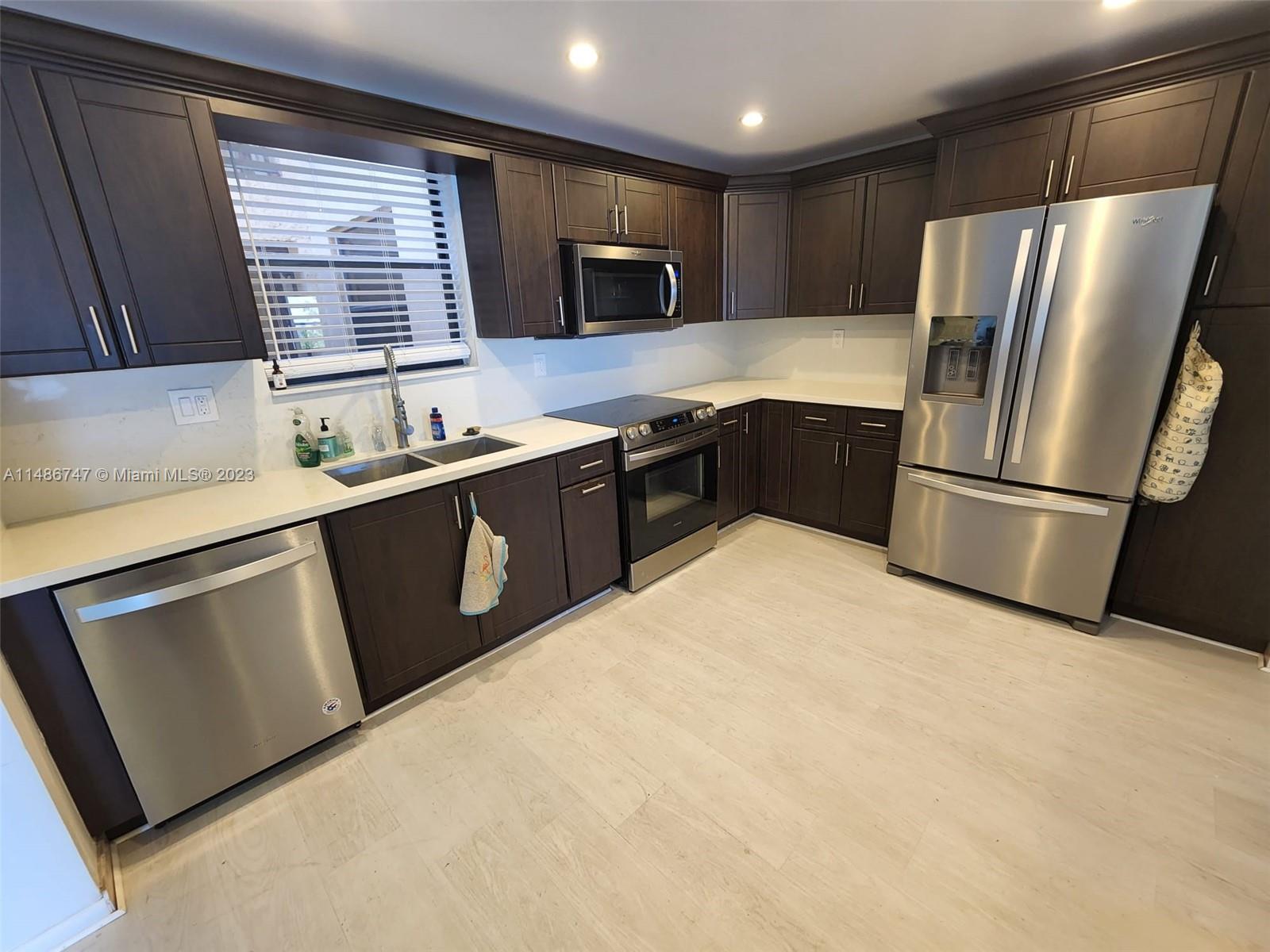 a kitchen with granite countertop a refrigerator stove microwave and sink