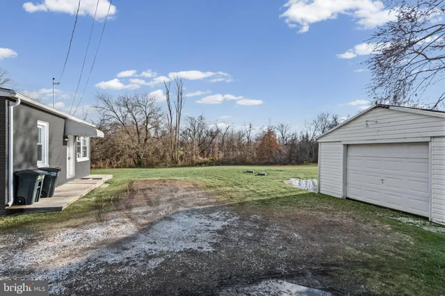 a white house with a big yard and large trees