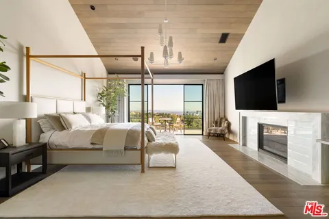 a spacious bedroom with a bed and glass walk in closet