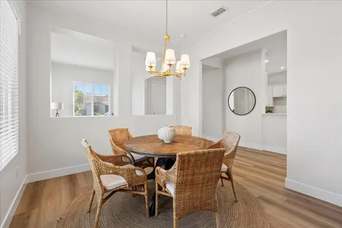 a dining room with furniture a chandelier and wooden floor