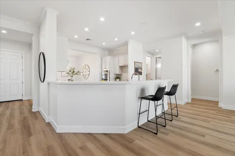 a kitchen with kitchen island stainless steel appliances a table chairs refrigerator sink and cabinets