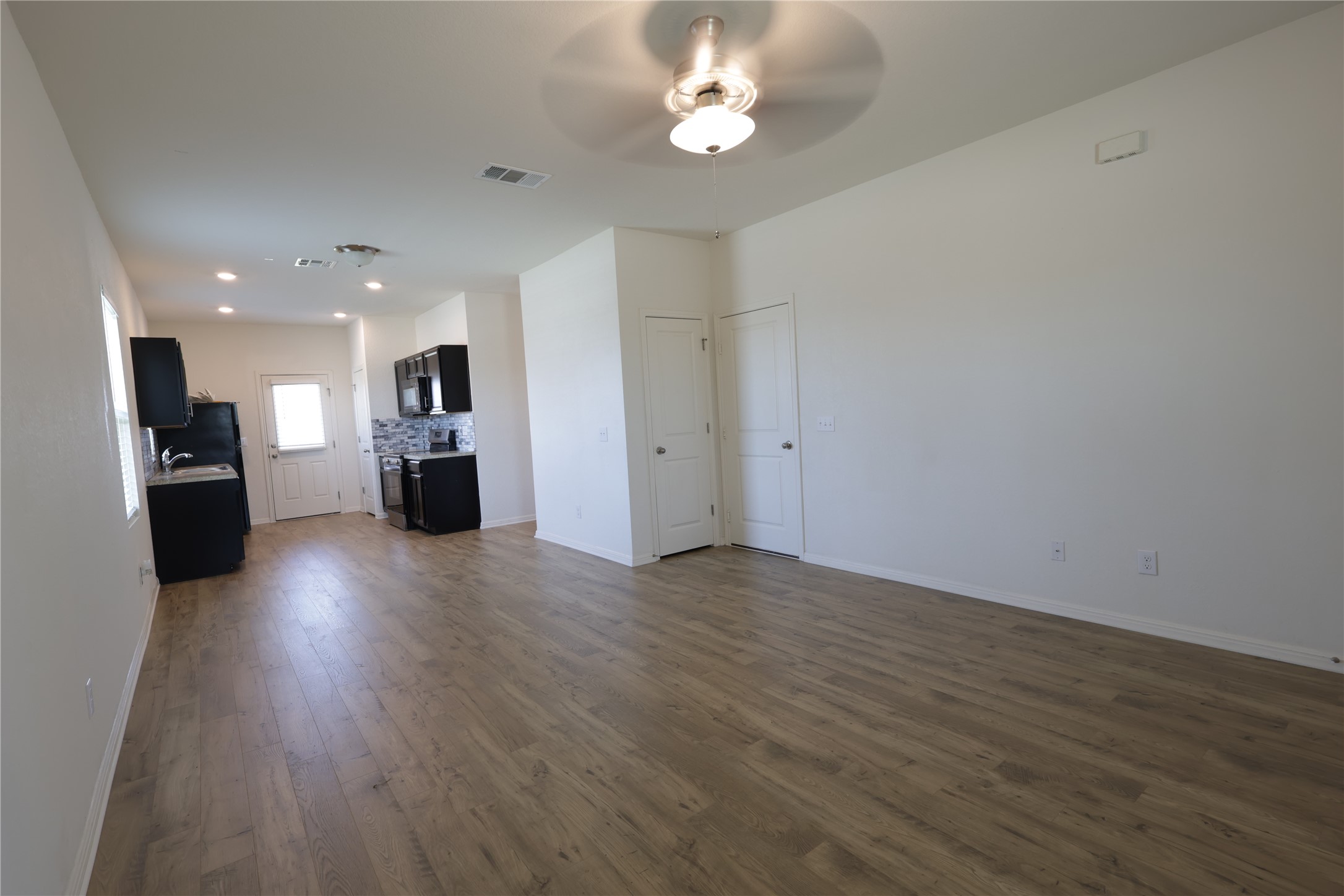250 Seneca Loop Kyle, TX 78640 - Photo 3 of 22 A well-lit interior space features resilient flooring, a functional kitchen, and modern lighting fixtures.