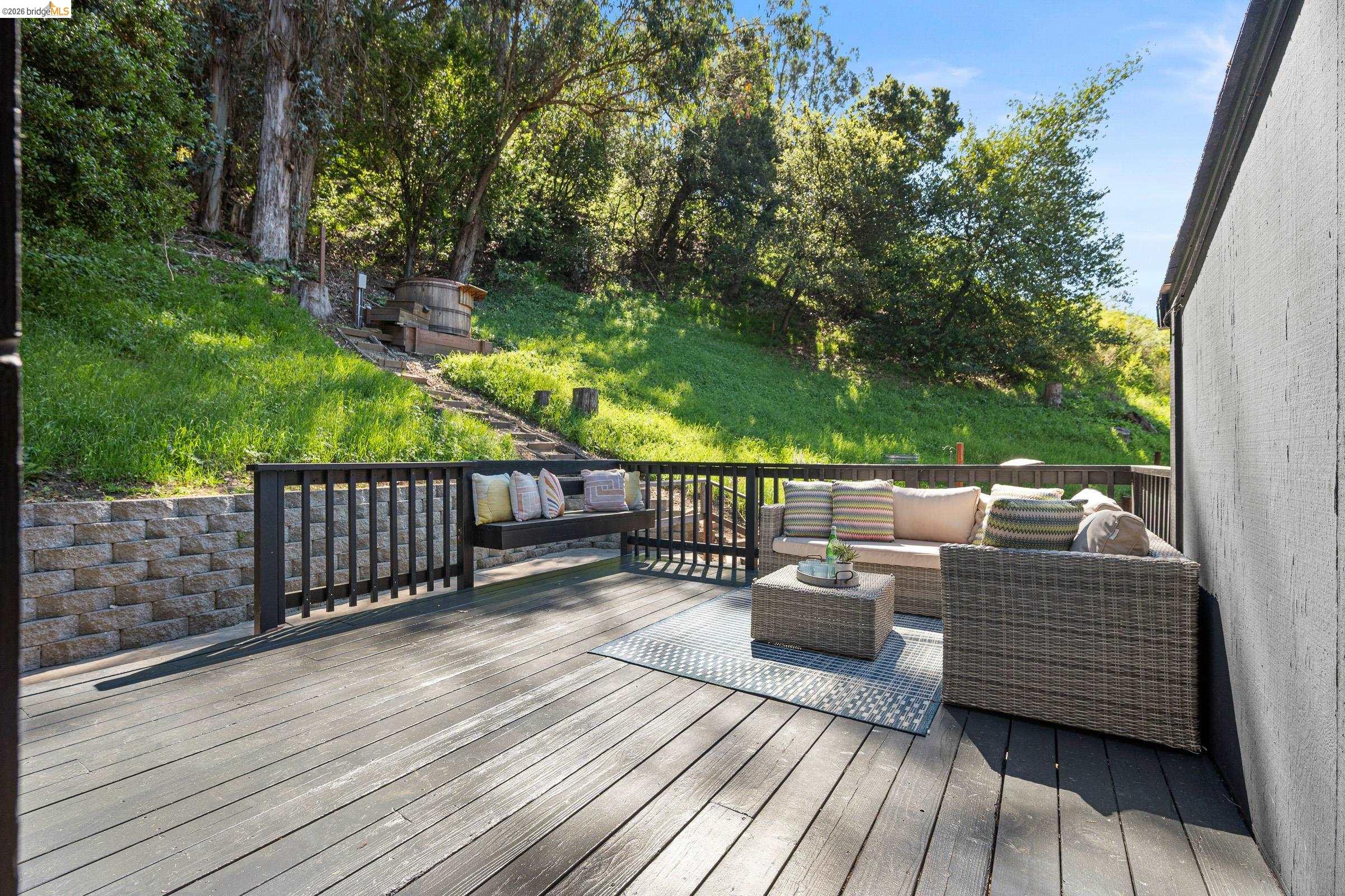 6600 Heather Ridge Way Oakland, CA 94611 - Photo 62 of 66 Expansive outdoor deck featuring dark wood-finish decking, black railings, and a retaining wall
