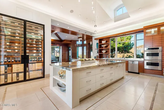 a large white kitchen with granite countertop a large window and white stainless steel appliances