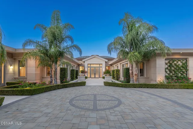 a front view of a house with a yard and potted plants