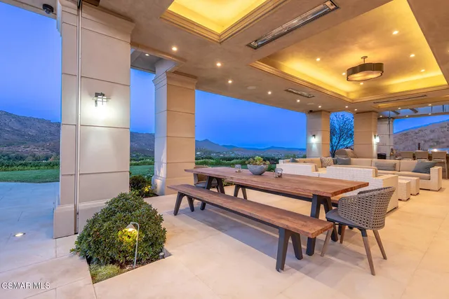 a outdoor space with chairs a rug and a large tree