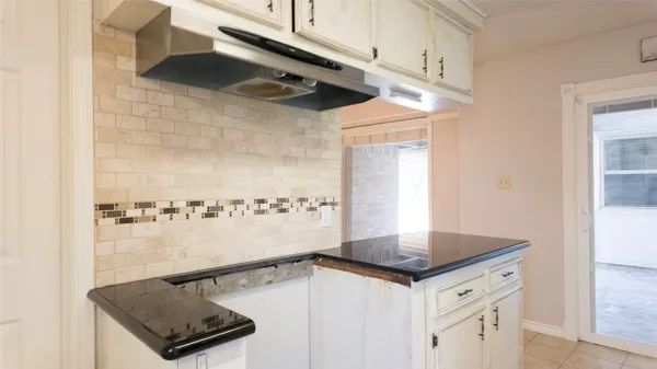 a kitchen with a sink a stove and white cabinets