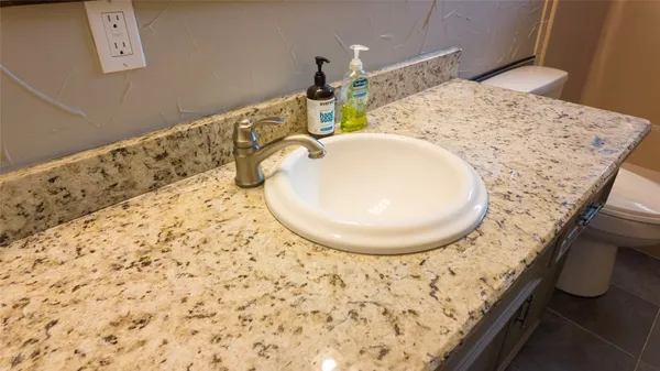 a bathroom with a granite countertop sink a mirror and a shower